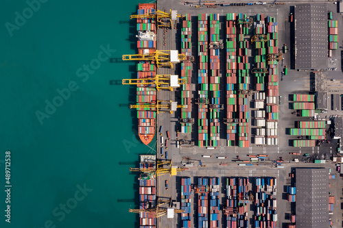 container ship at sea port and working crane bridge loading container for import export, international by shipping or transportation concept photograph from drone