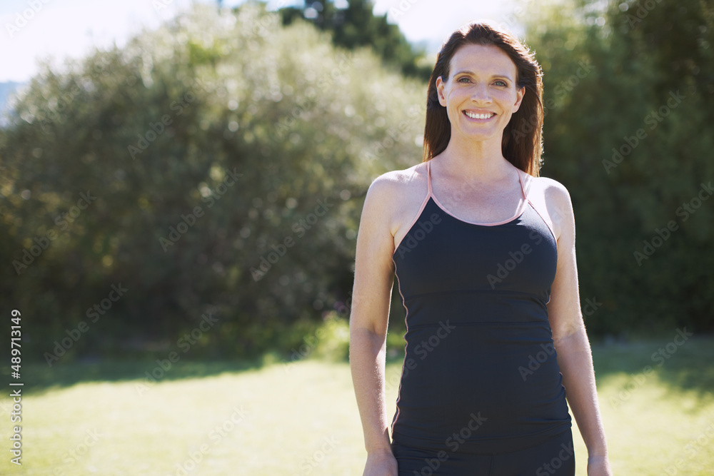 The outdoors is a place of rest for her. An attractive woman in sports clothing smiling while standing in the outdoors. The outdoors is a place of rest for her. An attractive woman in sports clothing smiling while standing in the outdoors.