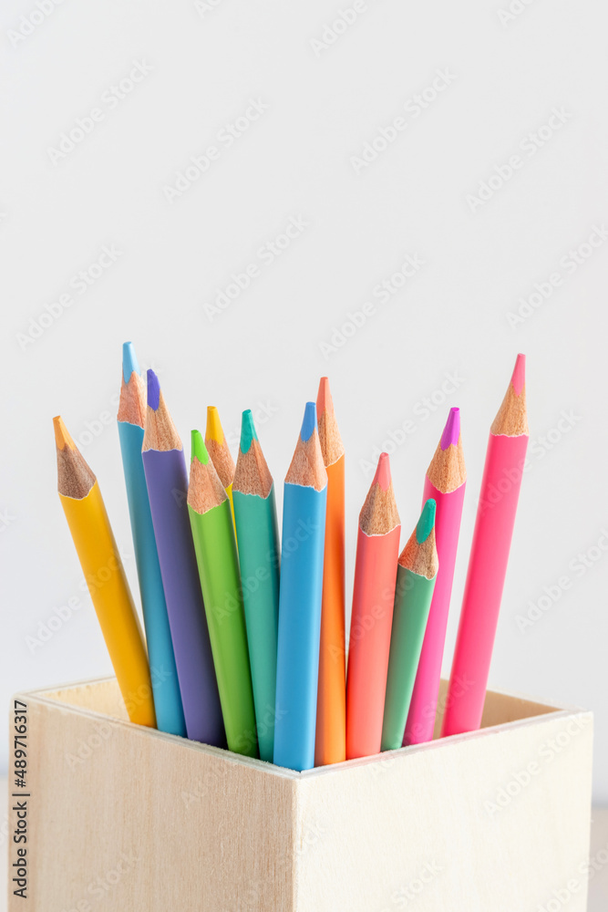 Fototapeta premium Several pastel colored pencils in wooden holder close-up