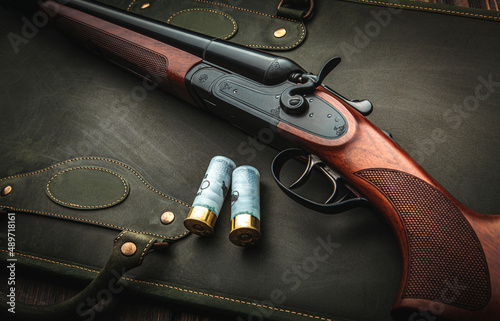Classic trigger double-barreled hunting rifle on a green background. Smooth-bore hunting rifle open for reloading. Concept postcards for hunters. photo