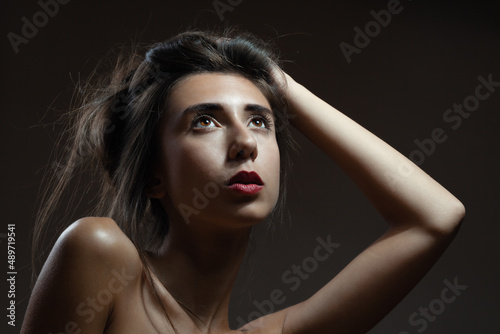 Beautiful girl portrait. Brunette lady on dark background. Serious face expression.