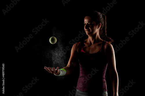 Tennis player girl with magnesium powder on her hands, grabbing a ball with dust visible.