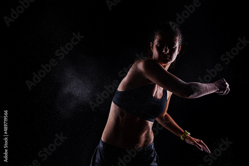 Kickboxer kirl with magnesium powder on her hands, punching with dust visible. © Nikola Spasenoski