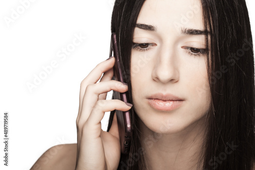 studio portrait of a beautiful brunette girl using phone against white backgroung.