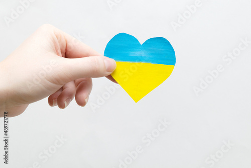 The concept of ending the war in Ukraine. heart in the colors of the flag of Ukraine in female hands.