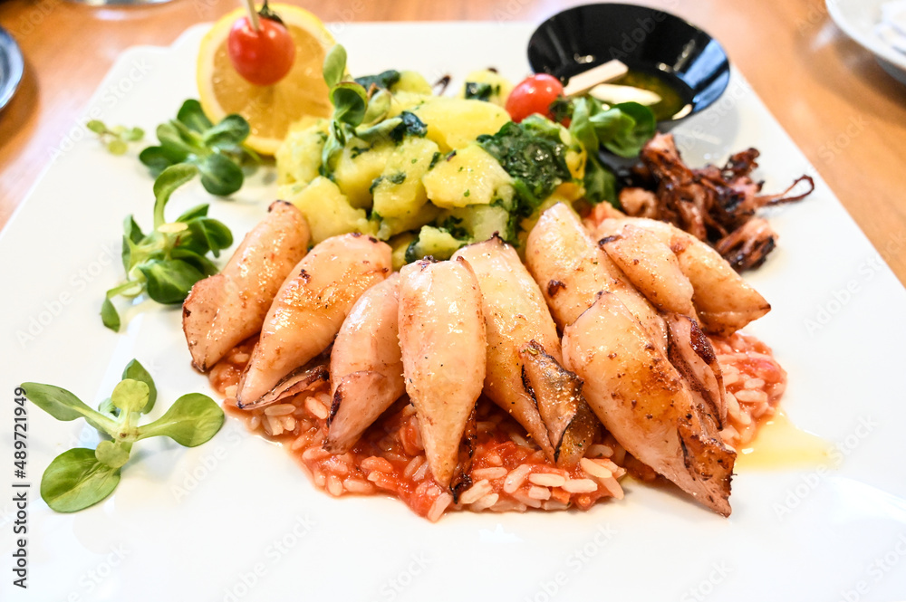 Grilled squid with chard and potatoes served on a plate in a restaurant. Healthy seafood. Grilled squid with chard and potatoes served on a plate in a restaurant. Healthy seafood.