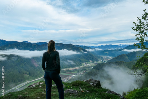 Woman admiring the scenic view from below mount Roethelstein near Mixnitz in Styria, Austria. Landscape of green alpine meadows and a small village in the valley of Grazer Bergland in Styria, Austria. photo