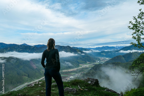Woman admiring the scenic view from below mount Roethelstein near Mixnitz in Styria, Austria. Landscape of green alpine meadows and a small village in the valley of Grazer Bergland in Styria, Austria. photo