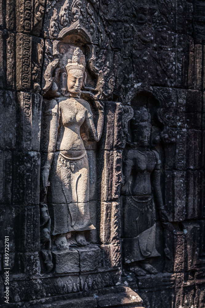 Stone bas-relief of ancient Khmer goddess on the temple wall in Angkor complex, Siem Reap, Cambodia
