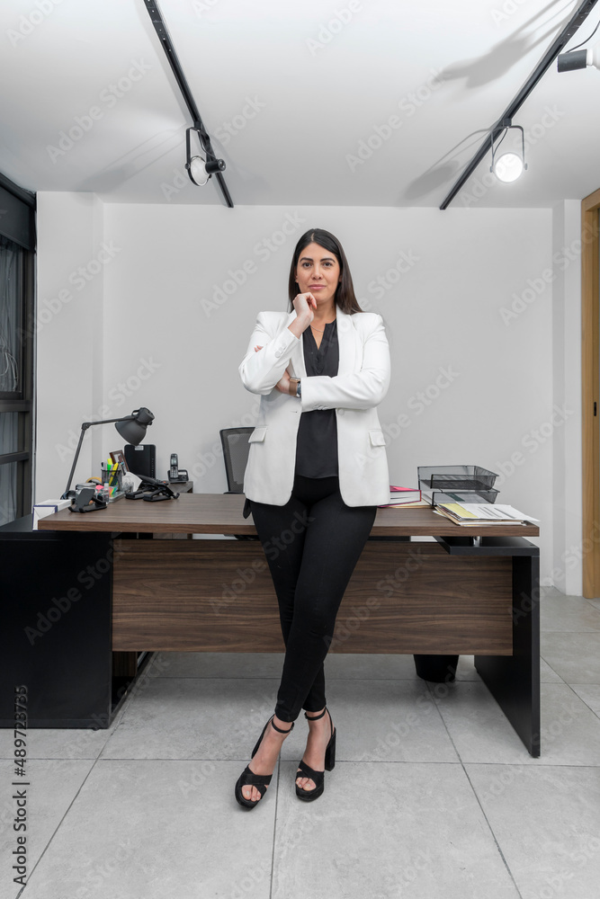 Portrait of a smiling young business woman with her arms crossed looking at the camera. Successful woman in her office smiling at the camera