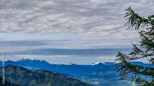 Panoramic view on the Eisenerzer Alps from below mount Roethelstein near Mixnitz in Styria  Austria. Snow capped mountain of the Ennstal Alps beyond the Grazer Bergland in Styria  Austria. Overcast