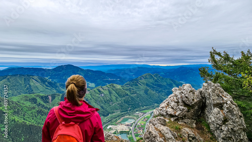 Woman admiring the scenic view from the summit of mount Roethelstein near Mixnitz in Styria, Austria. Landscape of green alpine meadows and hill in the valley of Grazer Bergland in Styria, Austria.