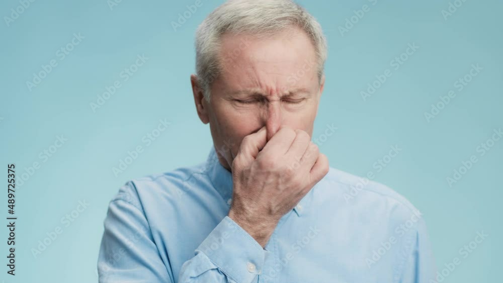 Stinky smell. Disgusting senior grey-haired man covering his nose, hiding from disgusting aroma and frowning Stinky smell. Disgusting senior grey-haired man covering his nose, hiding from disgusting aroma and frowning