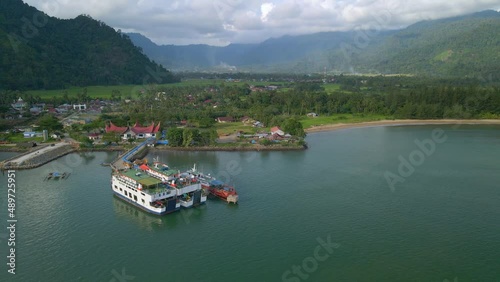 Indonesia, Sumatra Occidental. Wide shot of drone orbiting around tow ferries and one boat at dock in hrabor. photo