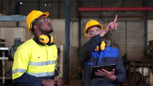 Diversity colleague of industry heavy team engineer. Inspection professional, technician, worker wearing safety uniform, helmet while checking and discuss maintenance machine line production factory.