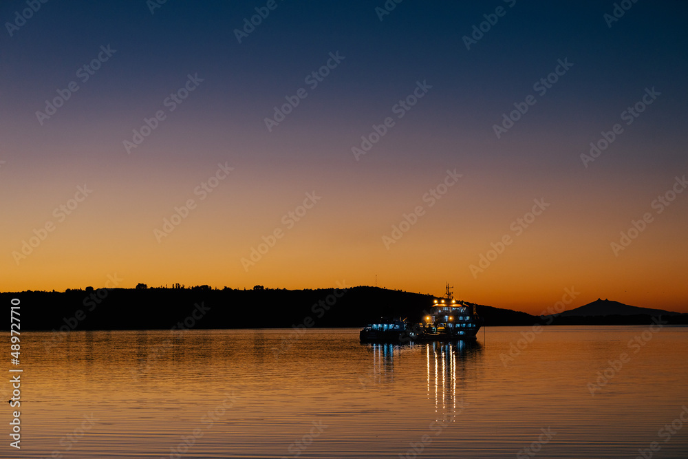 Fishing vessel seen from the shore during sunrise hour