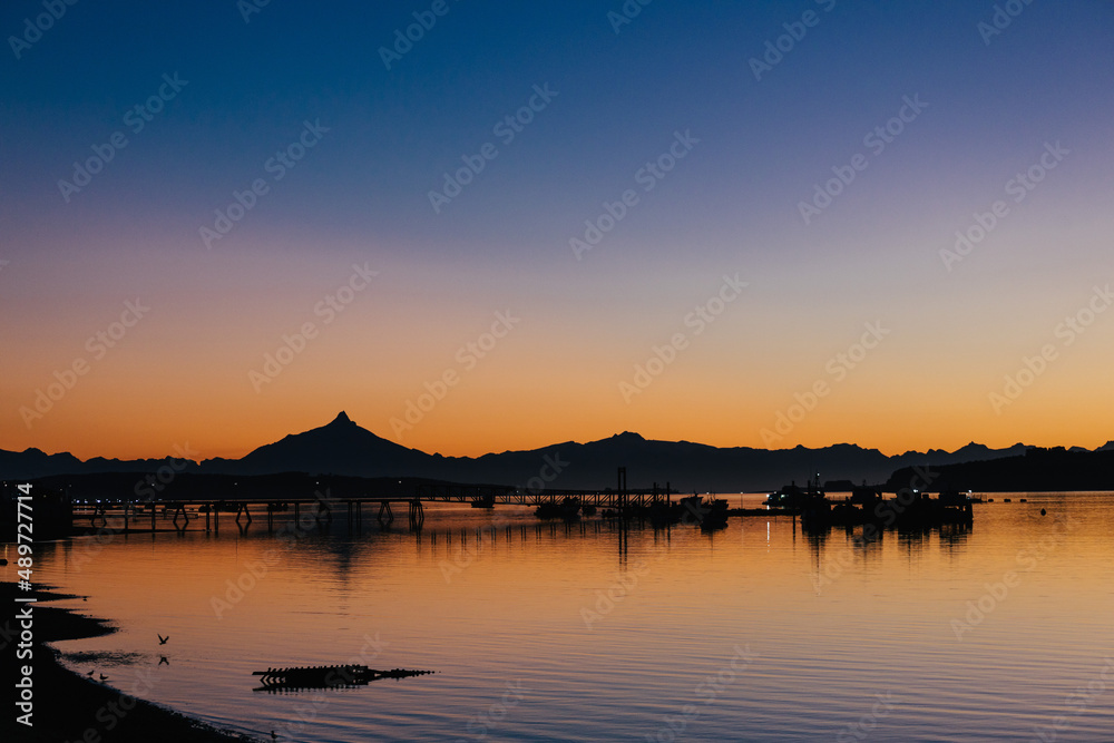 A port seen during the sunrise hour with a mountain range behind it