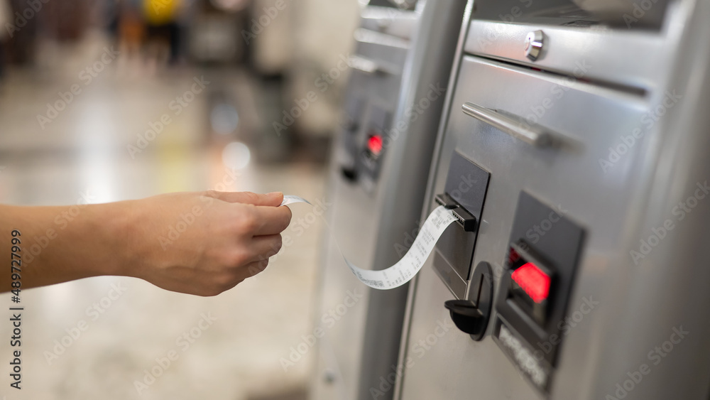 A woman takes a printed check from an ATM. A woman takes a printed check from an ATM.