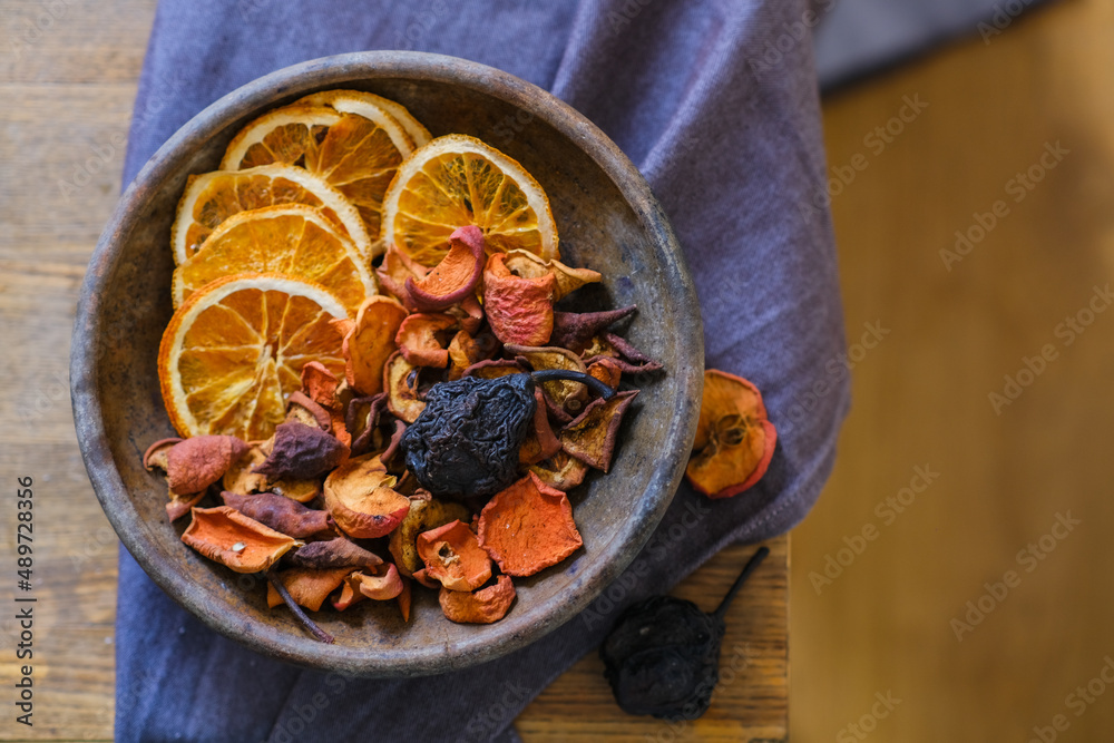 Dried fruits in an old clay plate on a wooden table. Compote. Uzvar. Traditional Ukrainian drink, apple, orange, pear, nutritional supplement, healing, balanced diet, vegan food, vitamins and minerals