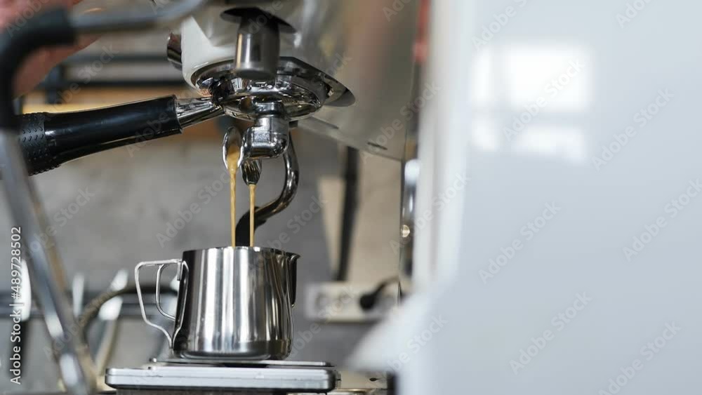 The process of making coffee in a coffee machine. The barista's hands move the poured stainless steel mugs to the side after preparation. Close up, dolly shot The process of making coffee in a coffee machine. The barista's hands move the poured stainless steel mugs to the side after preparation. Close up, dolly shot