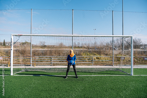Smiling ethnic woman with ball in goals on field