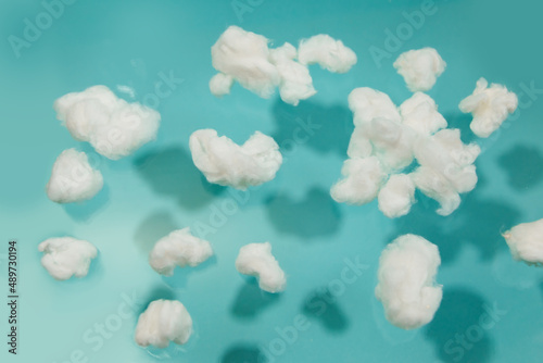 Photography White cotton fake clouds on a pastel blue background.