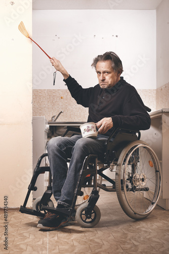 Old disabled man on wheel chair in his poor apartment