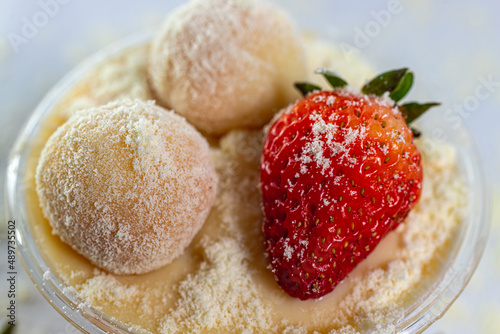 Doce beijinho com leite ninho em pó e morango fruta polvilhado sobre pasta de creme branco photo