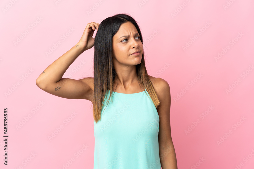 Caucasian girl isolated on pink background having doubts while scratching head Caucasian girl isolated on pink background having doubts while scratching head