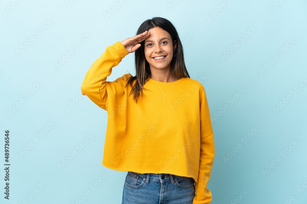 Caucasian girl isolated on blue background saluting with hand with happy expression Caucasian girl isolated on blue background saluting with hand with happy expression