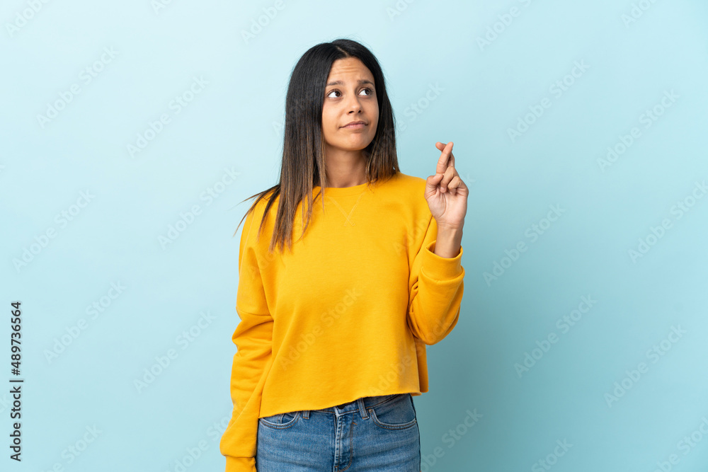 Caucasian girl isolated on blue background with fingers crossing and wishing the best Caucasian girl isolated on blue background with fingers crossing and wishing the best