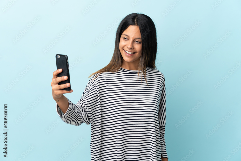 Caucasian girl isolated on blue background making a selfie Caucasian girl isolated on blue background making a selfie