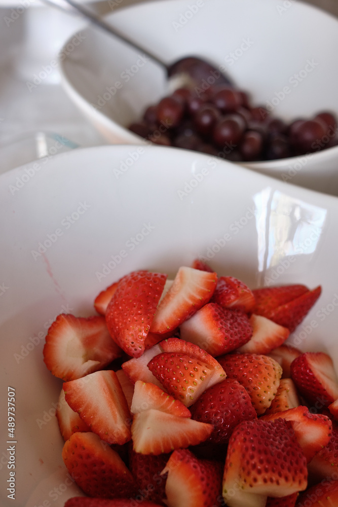 Fresh organic strawberries and grapes site in beautiful porcelain bowls ready for a healthy brunch or snack Fresh organic strawberries and grapes site in beautiful porcelain bowls ready for a healthy brunch or snack