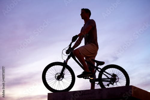 King of the city. Silhouette shot of a man riding his bike at dusk.