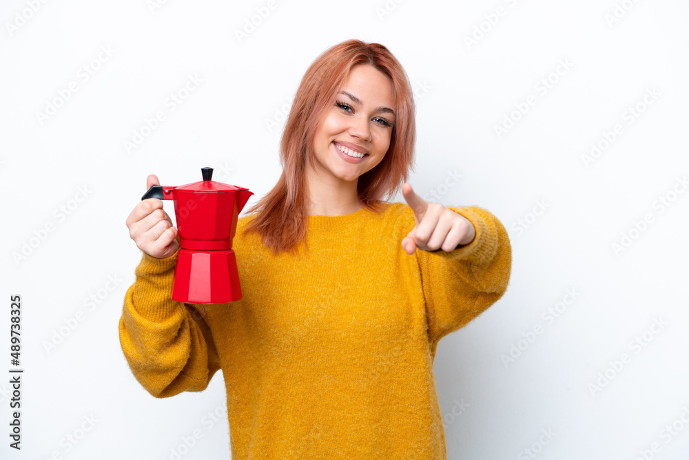 Young Russian girl holding coffee pot isolated on white background points finger at you with a confident expression Young Russian girl holding coffee pot isolated on white background points finger at you with a confident expression