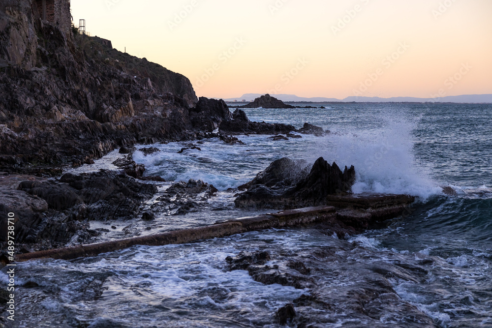 Coucher de soleil sur les vagues se fracassant sur les rochers au pied de Collioure (Occitanie, France)