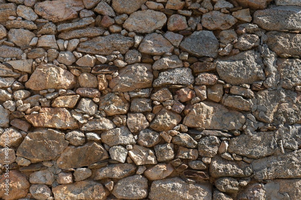 A old stone wall in which there are stones of different sizes, textures and colours, most of them are brown. A old stone wall in which there are stones of different sizes, textures and colours, most of them are brown.