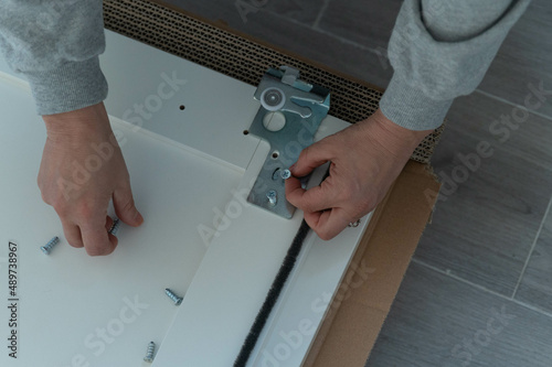 Wallpaper Mural Hands hold screws to attach iron fittings to white wooden boards on the floor, on top of cardboard. Torontodigital.ca