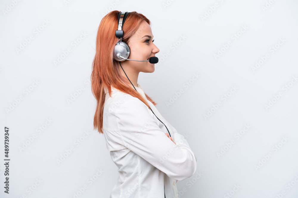Telemarketer Russian girl working with a headset isolated on white background in lateral position Telemarketer Russian girl working with a headset isolated on white background in lateral position