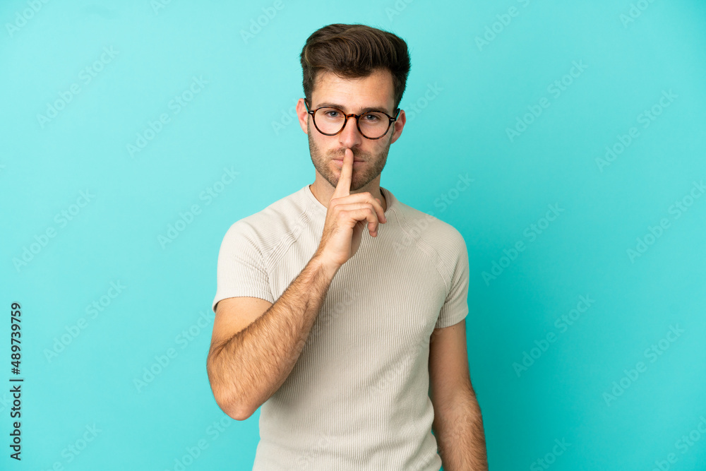Young caucasian handsome man isolated on blue background showing a sign of silence gesture putting finger in mouth Young caucasian handsome man isolated on blue background showing a sign of silence gesture putting finger in mouth