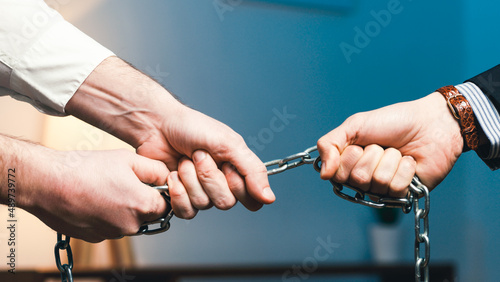 Hand of the boss in the office pulls an employee with a chain