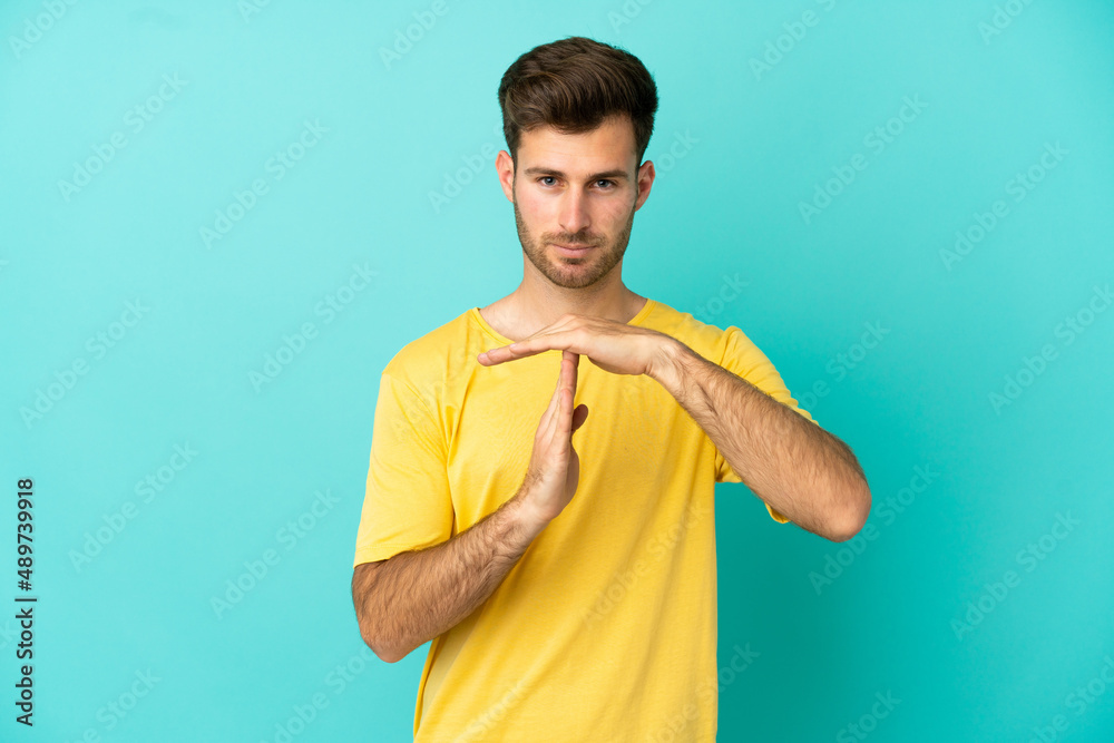 Young caucasian handsome man isolated on blue background making time out gesture Young caucasian handsome man isolated on blue background making time out gesture