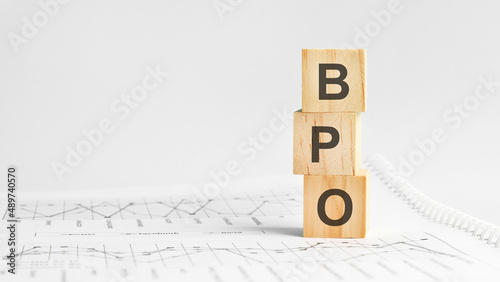 BPO - letters on wooden cubes. concept on cubes and diagrams on a gray background. business as usual concept imag.