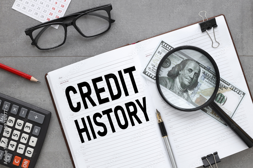 CREDIT HISTORY. open notepad with text. banknotes under a magnifying ...