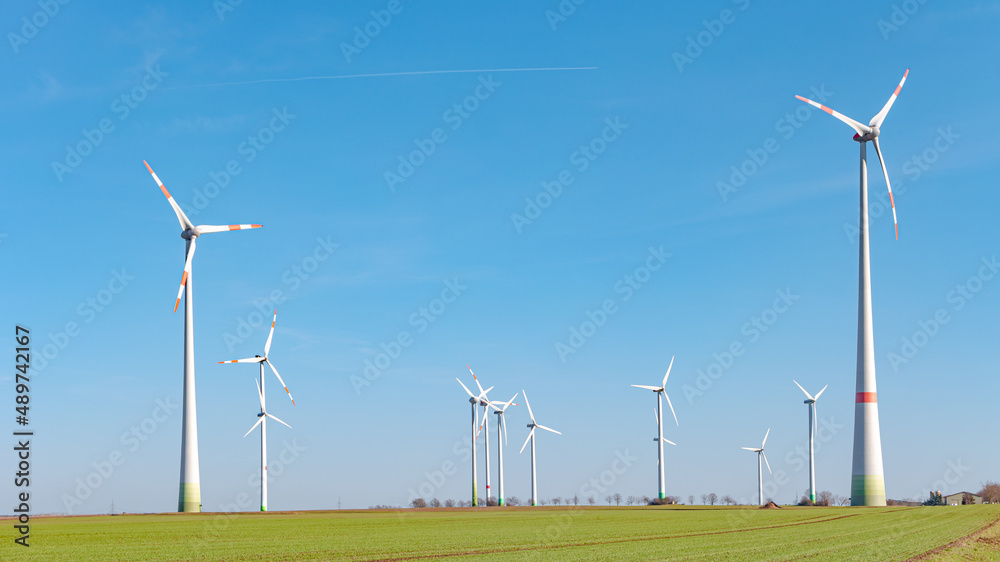 Panoramic view over beautiful farm landscape with early spring agriculture field, wind turbines to produce green energy near Mittweida, Germany, at blue sunny sky. Panoramic view over beautiful farm landscape with early spring agriculture field, wind turbines to produce green energy near Mittweida, Germany, at blue sunny sky.
