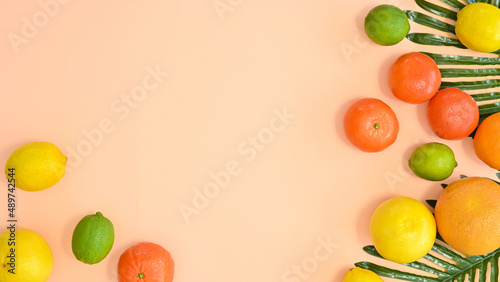 Summer tropic copy space arrangement with palm leaves and fresh organic citurs fruits on pastel beibe gackground. FLat lay creative