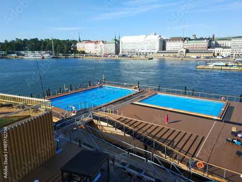 Helsinki, Finland - August 29, 2017: People bathe in an open public pool against the backdrop of the seaport and city buildings.