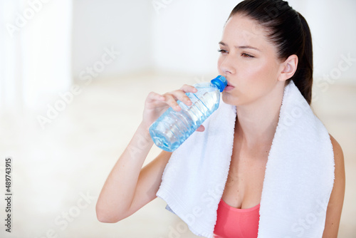 Its important to drink enough water. Young woman drinking water after a gym session.