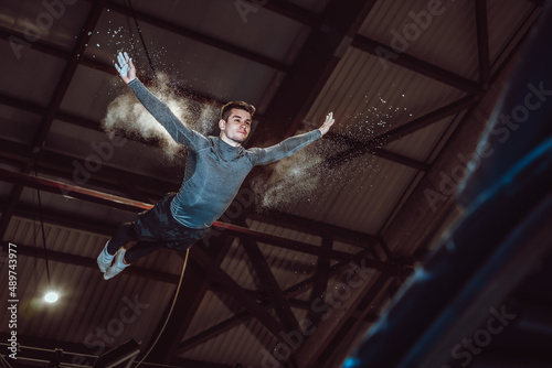 Young man jumping in trampoline inside the sport center. Mid-air