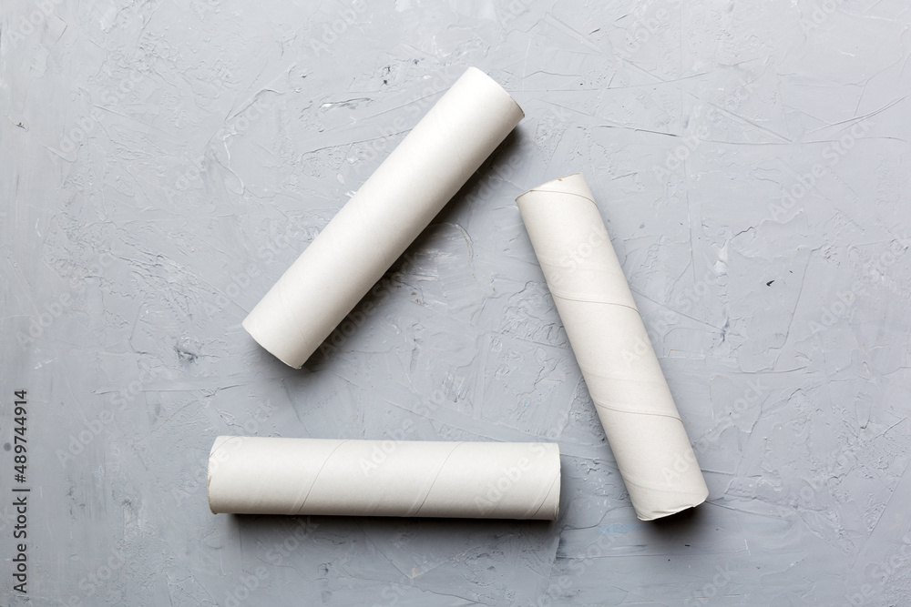 Empty toilet paper roll on colored background. Recyclable paper tube with metal plug end made of kraft paper or cardboard in the form of a recycling sign Empty toilet paper roll on colored background. Recyclable paper tube with metal plug end made of kraft paper or cardboard in the form of a recycling sign